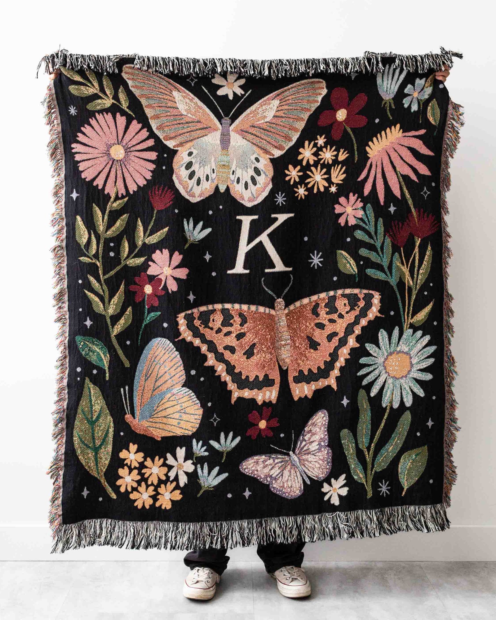 Decorative blanket with butterflies and flowers featuring a letter 'K' on a white background