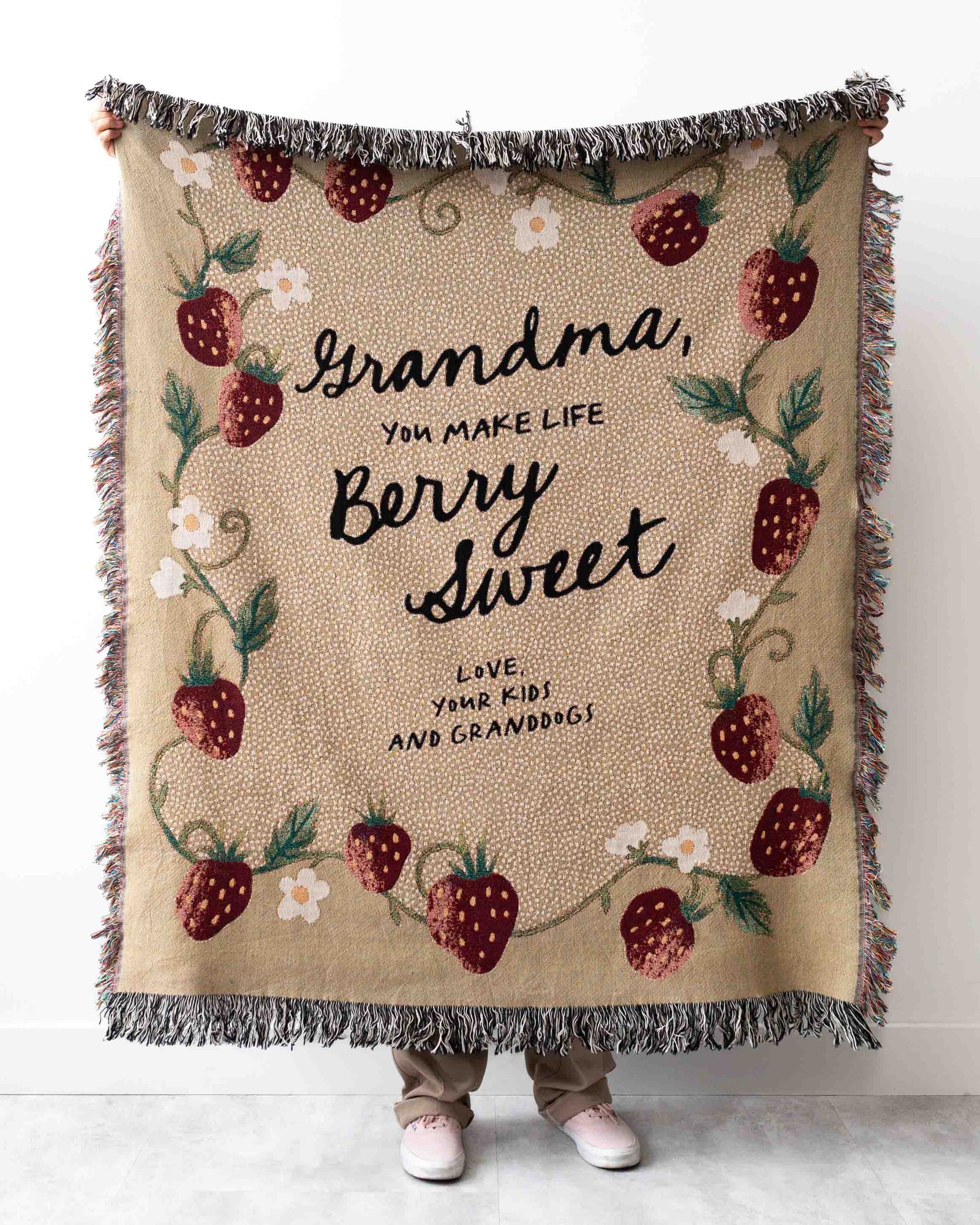 Blanket with strawberry pattern and text held by a person on a white background