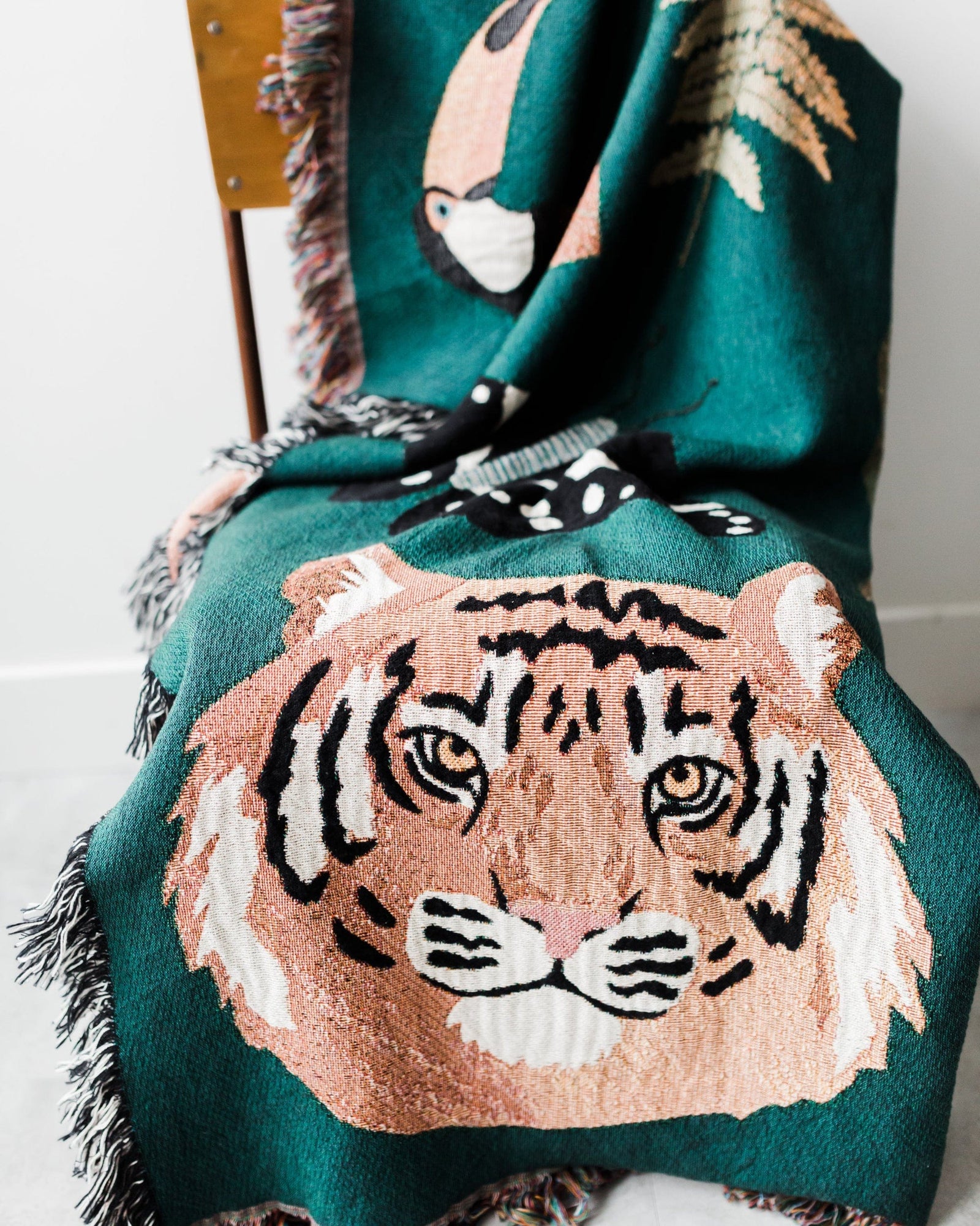 Teal blanket with a tiger design draped over a chair.