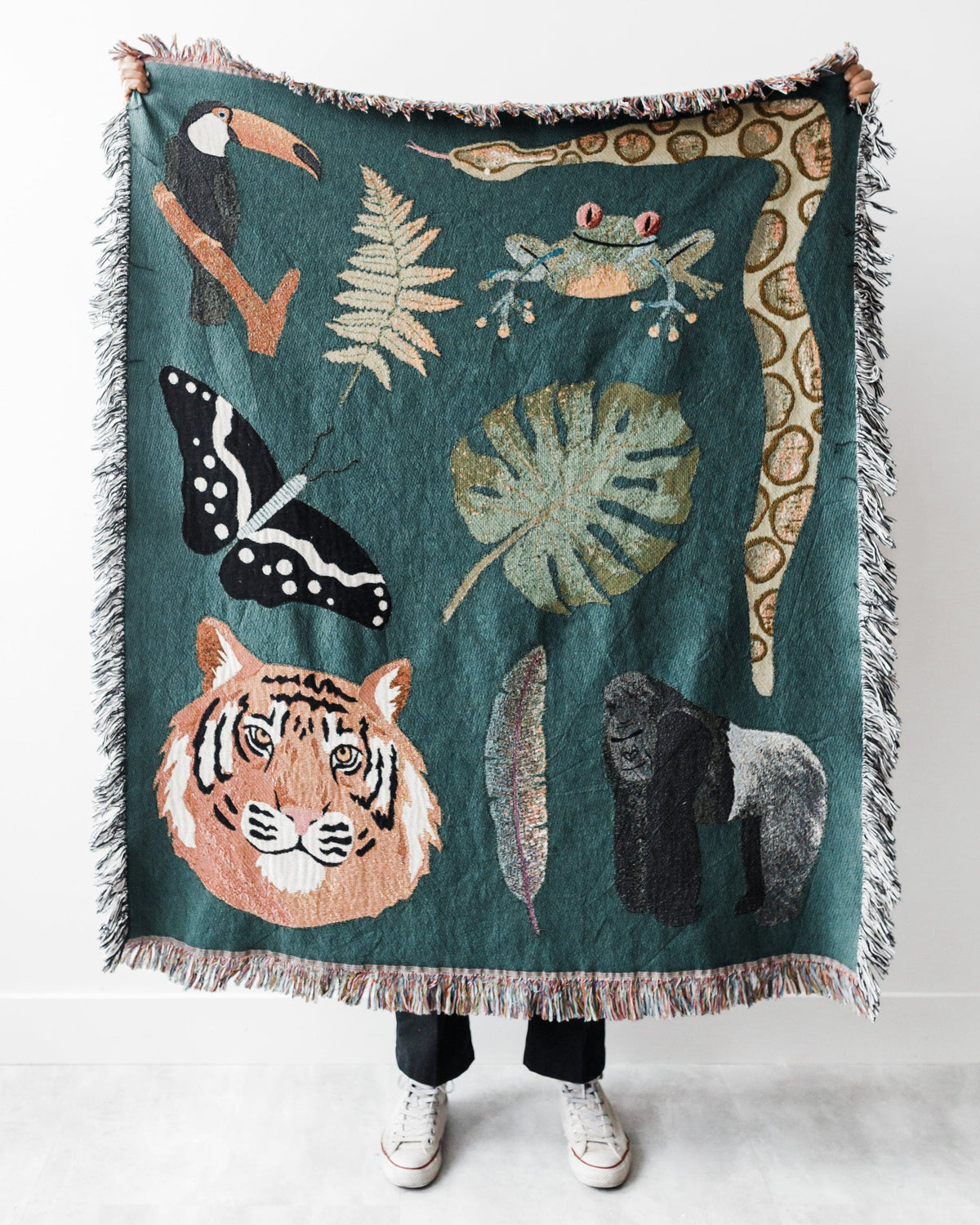 Person holding a teal blanket with animal and nature-themed designs on a white background