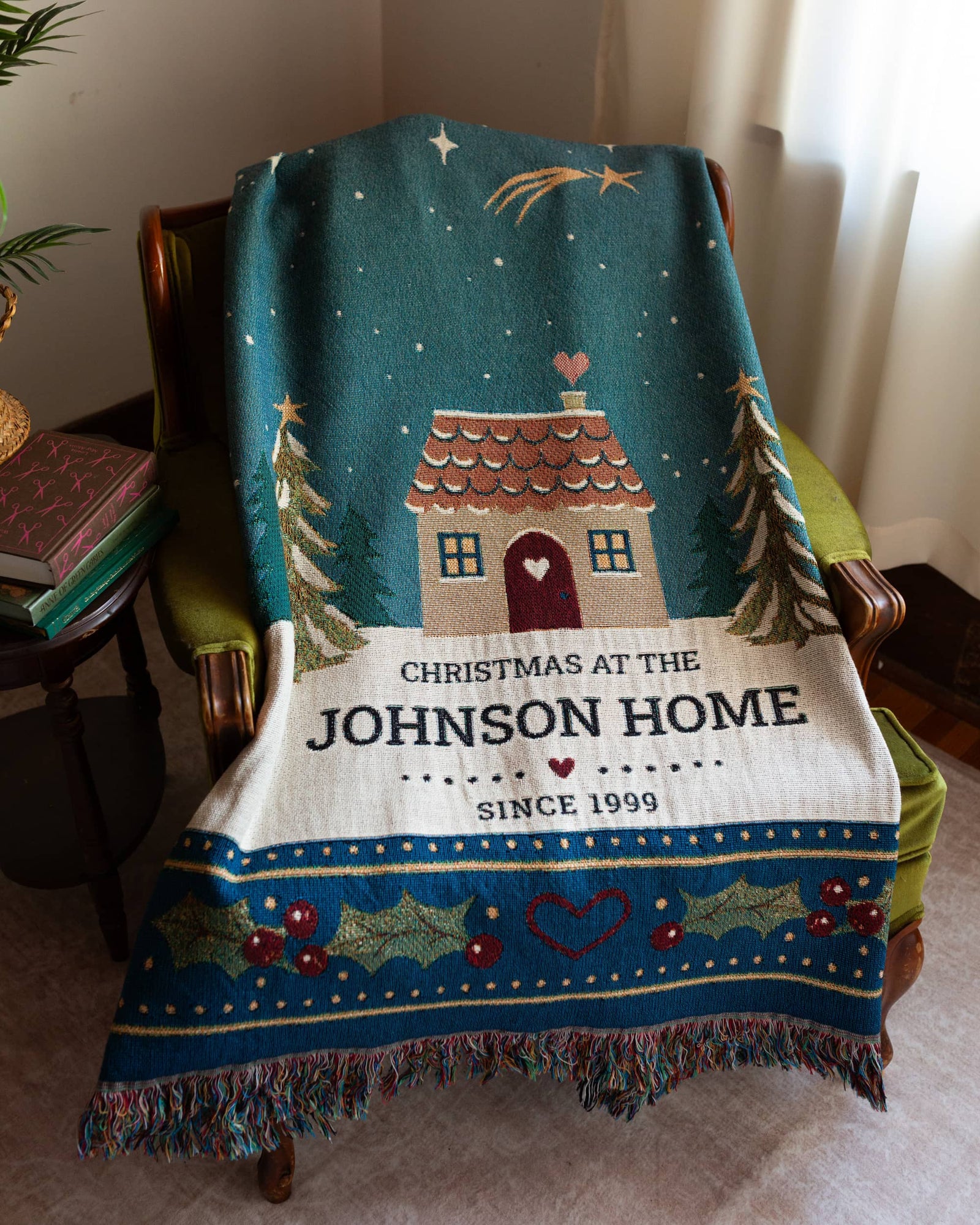 Personalized Christmas blanket with house design and text draped over a chair.