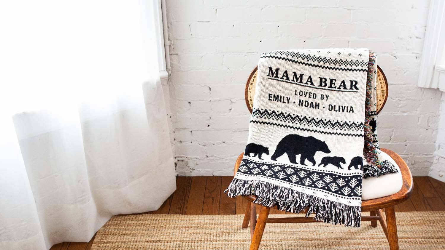 Mama Bear blanket with black text and bear illustrations draped over a wooden chair in a room.